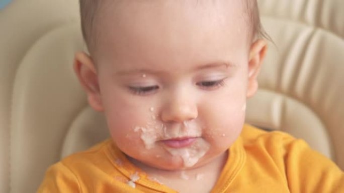 12-18个月大的小孩吃燕麦粥，翻盘。吃饭时有趣的脏娃娃脸