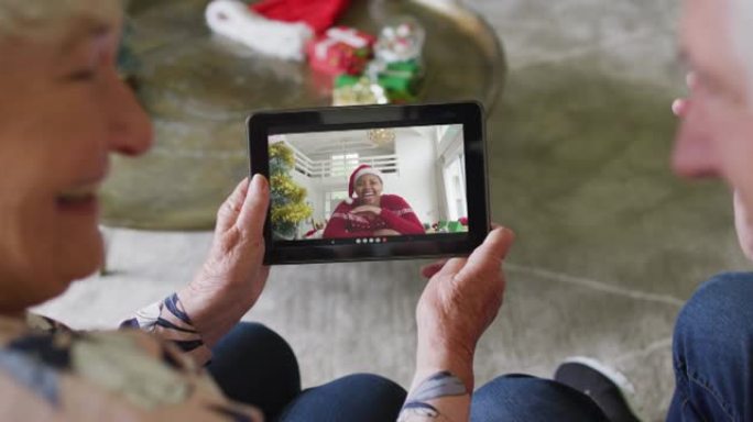 微笑的白人高级夫妇使用平板电脑与屏幕上的女人进行圣诞节视频通话