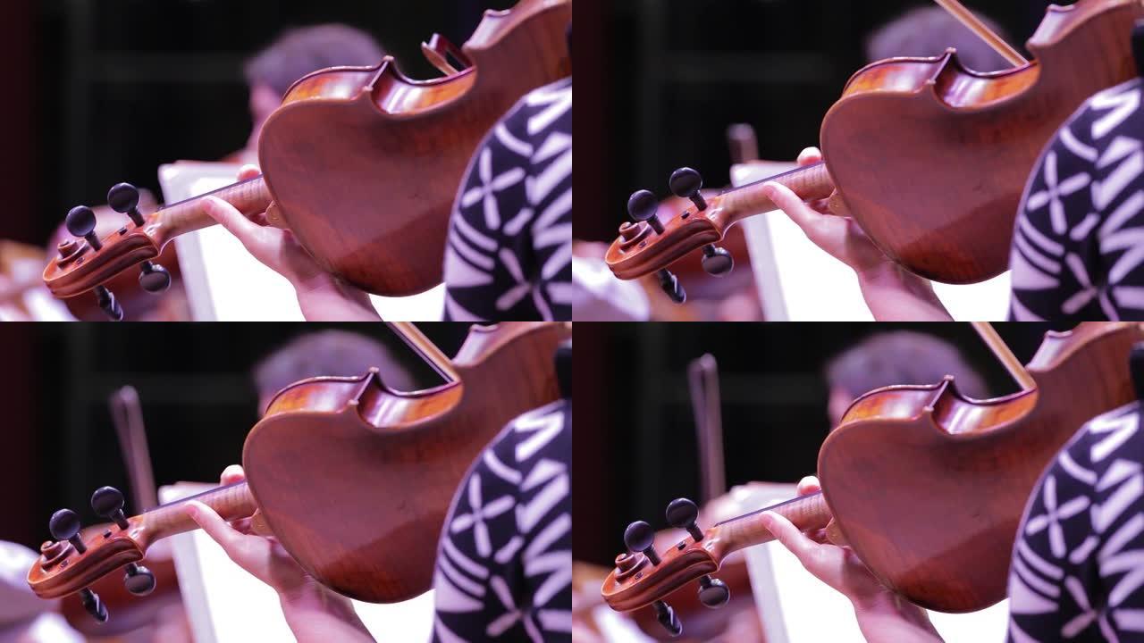 小提琴和乐器脖子上的手的特写镜头。交响乐团。小提琴家的演奏。