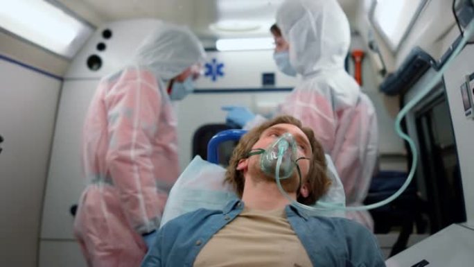 戴氧气面罩的男性患者在急救车中前往医院
