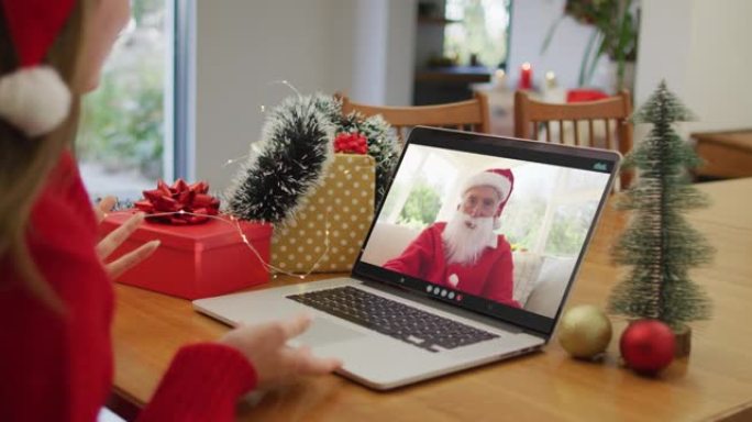 圣诞节时与圣诞老人进行笔记本电脑视频通话的白人妇女