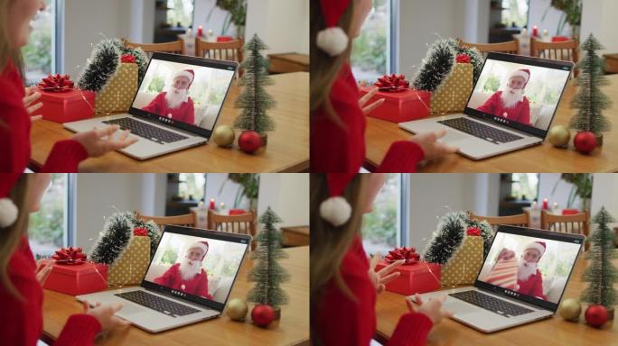 圣诞节时与圣诞老人进行笔记本电脑视频通话的白人妇女
