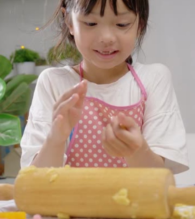 亚洲女孩拿着糕点面团，然后模制自制饼干庆祝圣诞节，生活方式概念。
