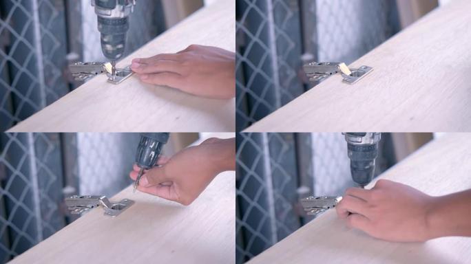工匠的手用螺钉将橱柜铰链安装在木制橱柜门上。有技巧