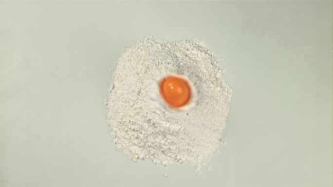 鸡蛋的超慢动作掉落在桌子上的一堆面粉中，并以1000 fps的速度在高速相机上拍摄。