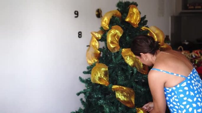 黑发女人在圣诞树上挂饰。