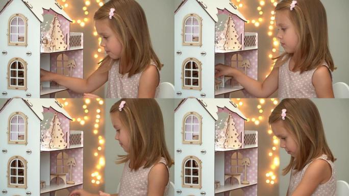 小女孩用玩具家具玩玩具屋。节日和礼物概念。新年，圣诞节