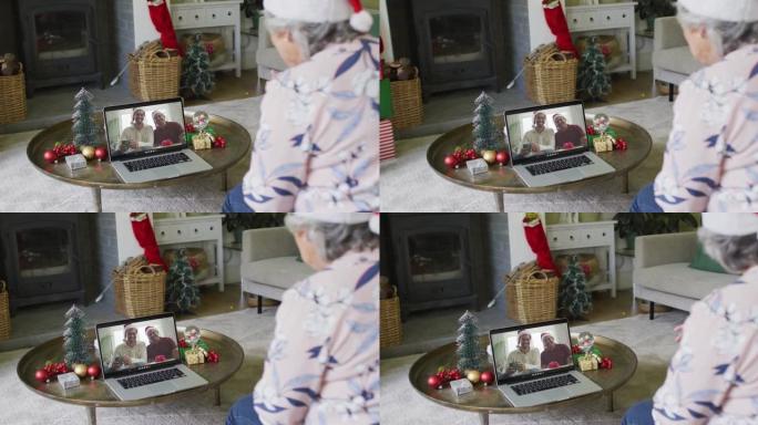 白人高级妇女使用笔记本电脑进行圣诞节视频通话，屏幕上有微笑的家人