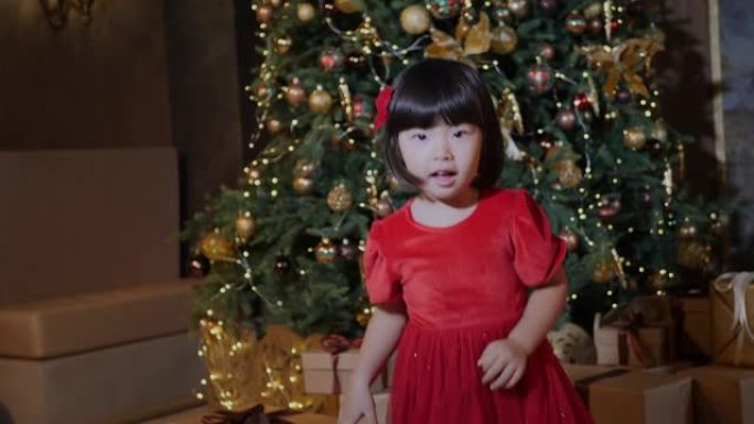 穿着红色连衣裙的韩国女童站在新年圣诞树上