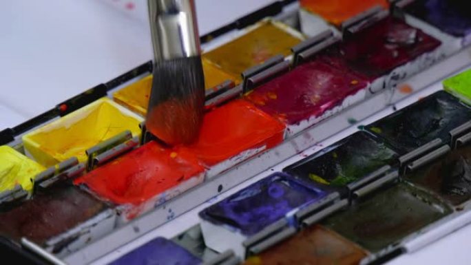 艺术家在画笔上涂上水彩颜料并绘画。