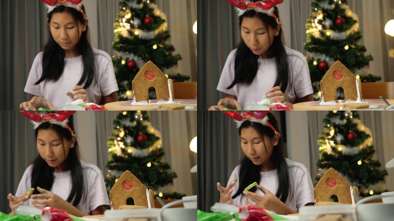 亚洲女孩在晚上在家做圣诞饼干和姜饼屋时舔手指上的糖，假期的生活方式概念。