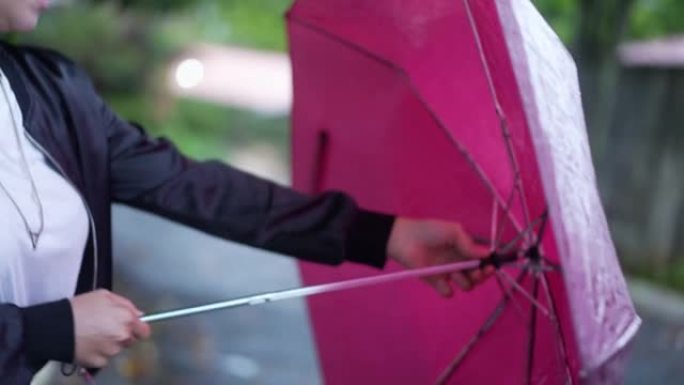 年轻女子在雨中行走时在城市街道外面打开雨伞