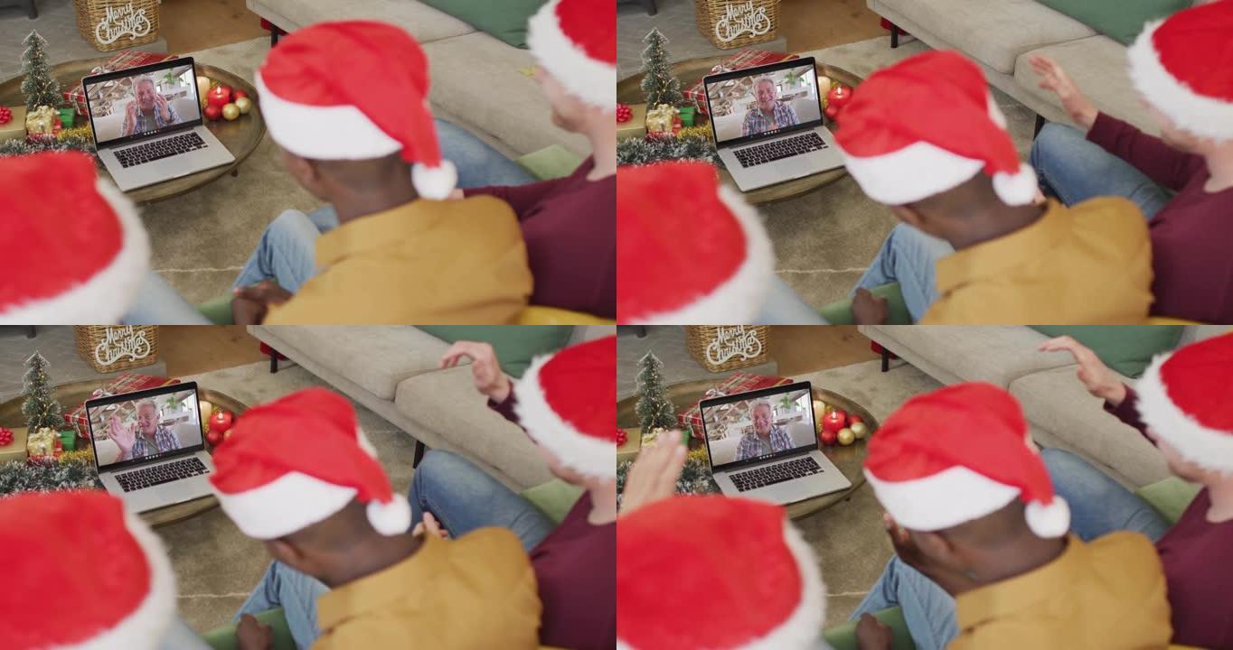拥有圣诞老人帽子的多元化家庭使用笔记本电脑进行圣诞节视频通话，屏幕上有快乐的男人