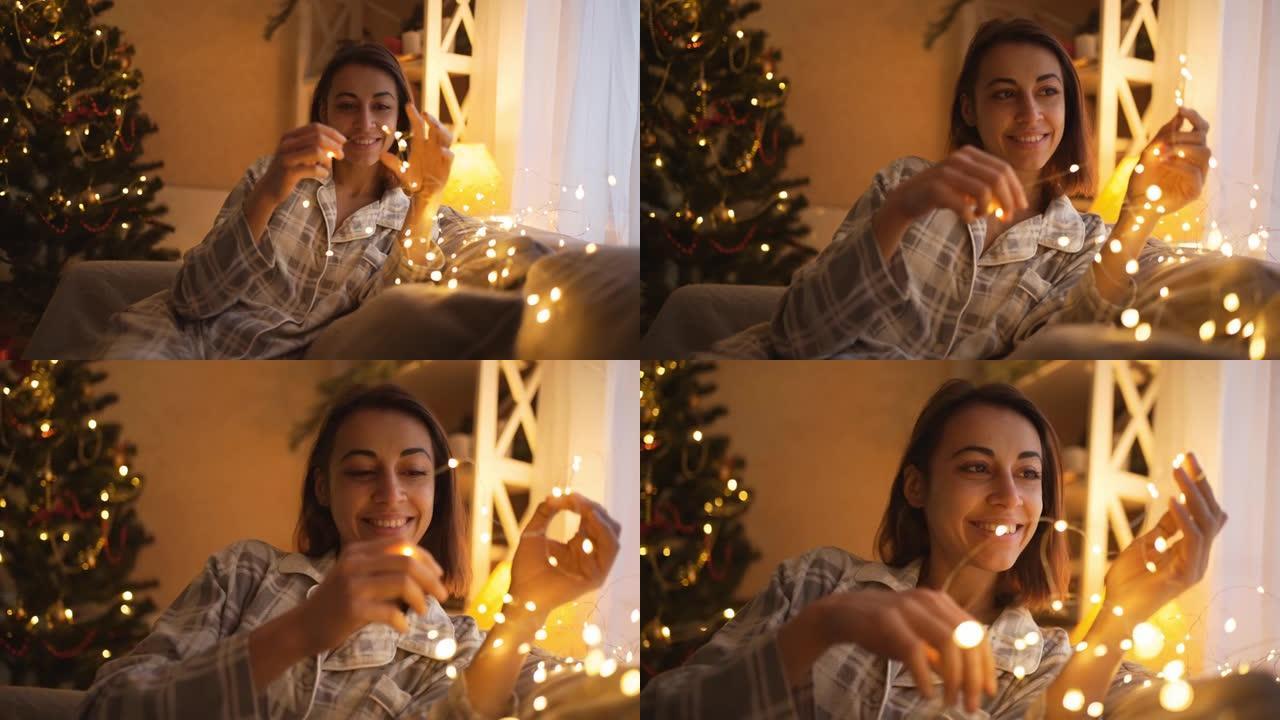 特写镜头快乐做梦的女孩拿着圣诞彩灯，等待奇迹发生在圣诞节和新年