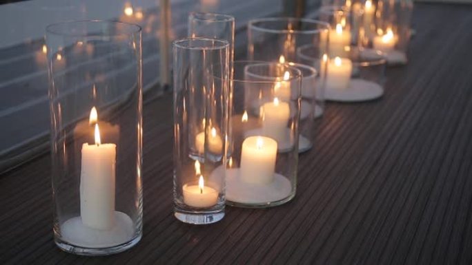 在地板上燃烧蜡烛。在地板上的透明玻璃烛台上燃烧的蜡烛是在优雅的玻璃花瓶中燃烧的蜡烛。浪漫的风景