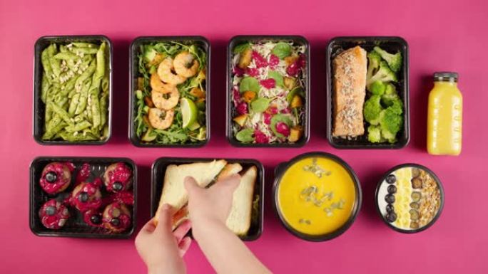 送餐俯视图，用一次性容器带走餐点。午餐盒的特写镜头，粉红色背景上有煮熟的素食菜肴。健康饮食。餐饮服务