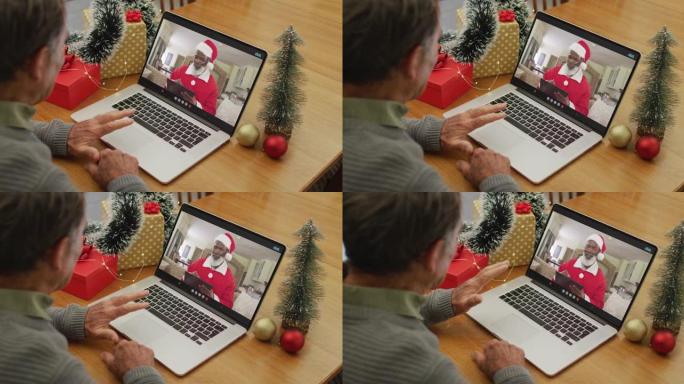 白人高级男子在屏幕上与非洲裔美国圣诞老人在笔记本电脑上进行圣诞节视频通话