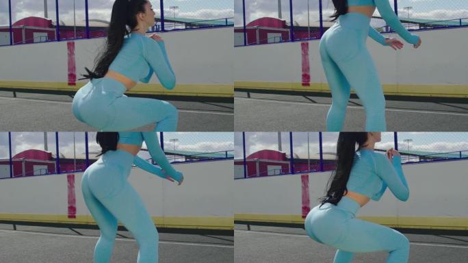 在街上的围栏区域进行健身锻炼时，穿着蓝色运动服的fit女性的特写镜头。街上的健身运动。健康的黑发女人