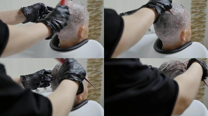 戴着手套的理发师的手在女学生的头发上涂上油漆