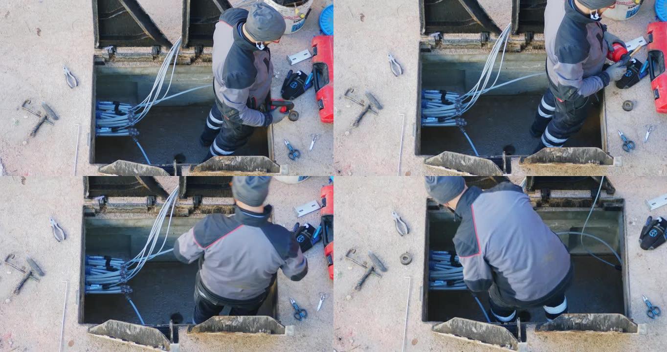 工人用电动拆除锤在光缆线路的钢筋混凝土竖井中闯入。开放式三角形铸铁井盖