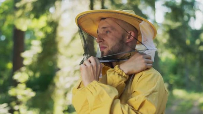 养蜂人准备在养蜂场的森林里用蜜蜂，蜂箱准备工作，他戴上了带有防护网的帽子，头上戴着蚊帐以保护他免受昆