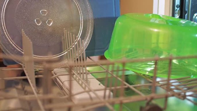 女人的手把脏盘子放在洗碗机里。家务
