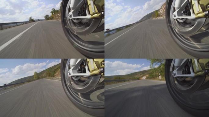 摩托车骑在自然界的道路上。在颠簸的沥青路面上关闭车轮。