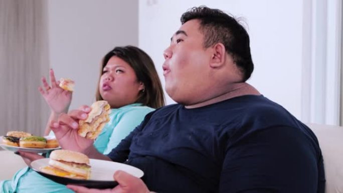 肥胖夫妇在家吃汉堡包和甜甜圈
