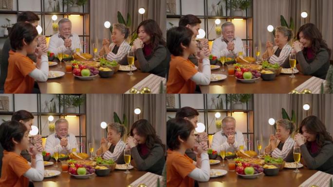 幸福亚洲多代人一起用餐，家庭手牵着手，在感恩节晚餐前祈祷，祖父母孙子孙女在感恩节传统晚餐回家
