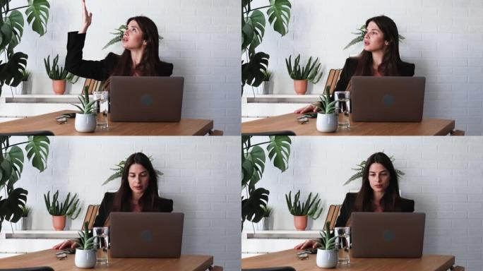 年轻成功的女商人坐在办公室里，在笔记本电脑上工作，由于楼上办公室正在装修，工人正在制造噪音，因此无法