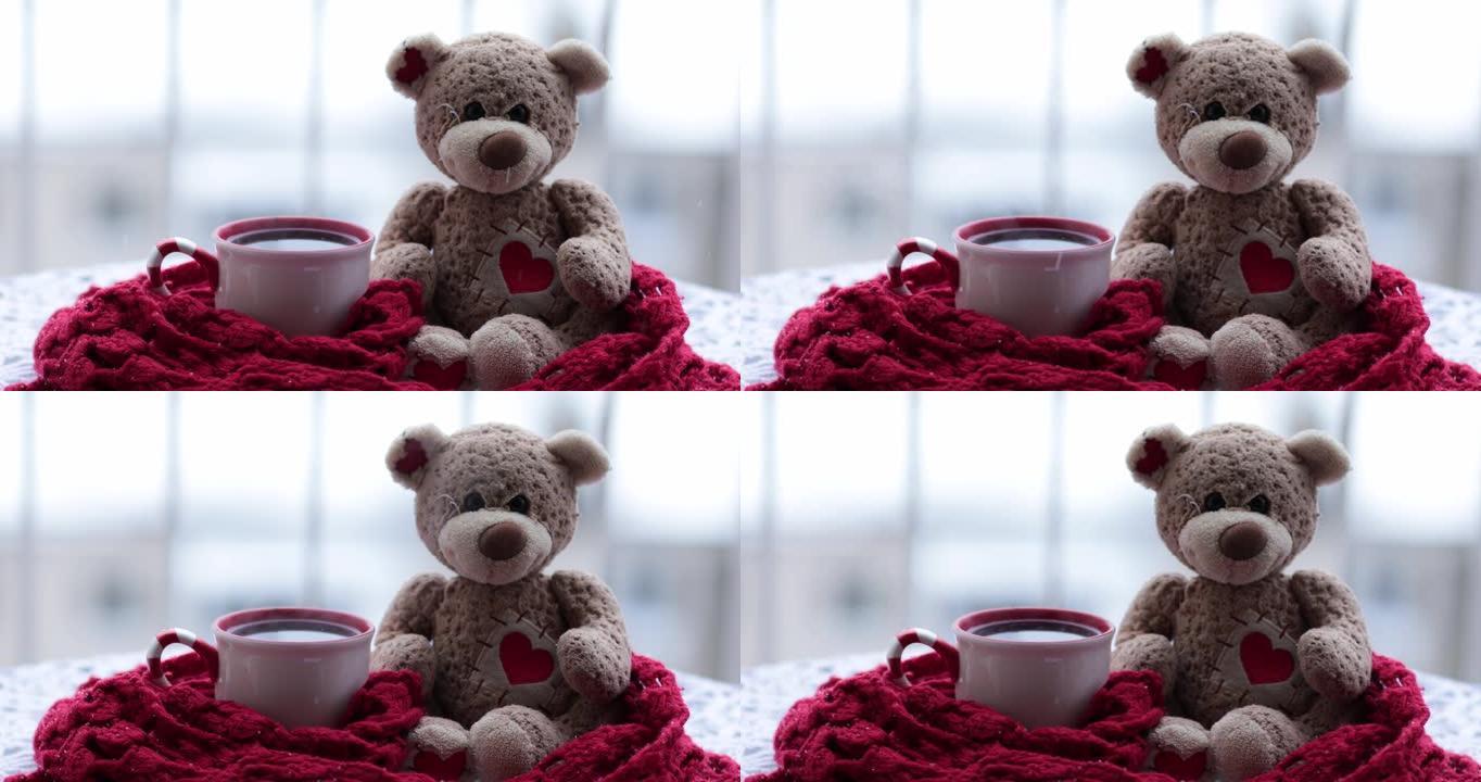 一杯热茶和泰迪熊包裹在雪地上的红色围巾上