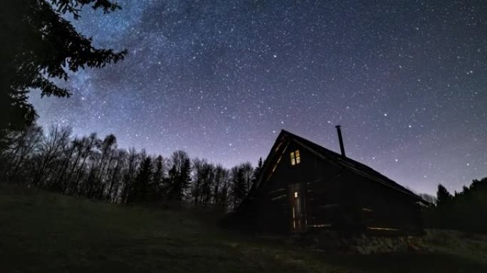 浪漫的星空和银河系在野生森林自然天文学延时4k的老木屋上快速旋转