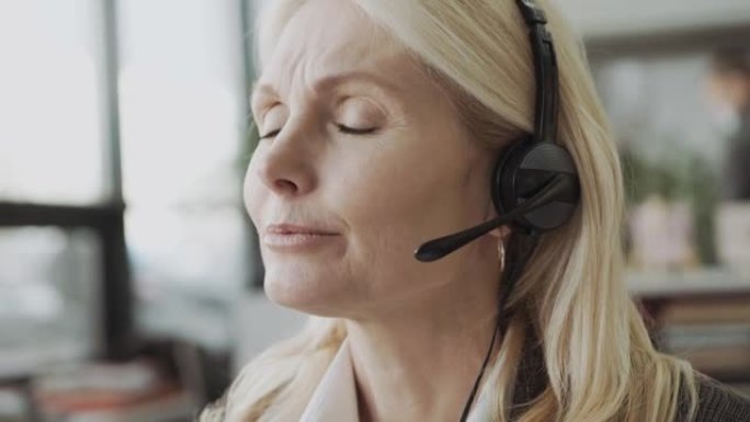 中年商务女性-办公室里戴着耳机的经理，并在网上提供建议