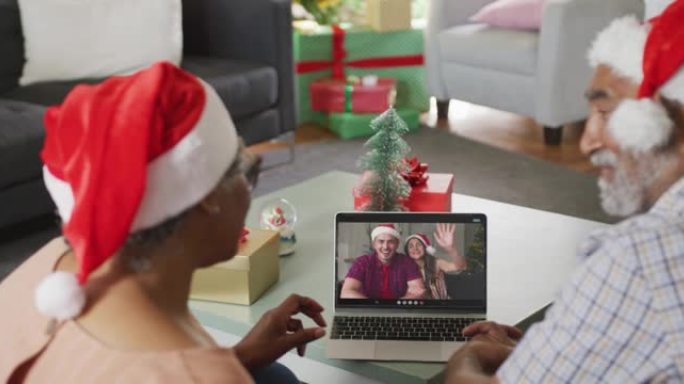快乐的高级非洲裔美国夫妇在圣诞节期间在笔记本电脑高加索夫妇上进行视频通话