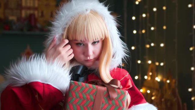 可爱的女孩角色扮演圣诞米库圣诞老人礼服与礼物。新年精灵。用手纠正她的头发