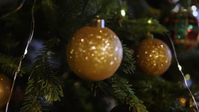 金色圣诞树玩具球挂在带有花环的圣诞树上