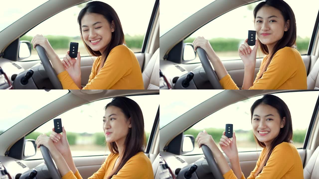 年轻漂亮的亚洲女性得到新车。她手里拿着车钥匙看着窗外，非常高兴和兴奋。灿烂的日子里，微笑的女性驾驶车