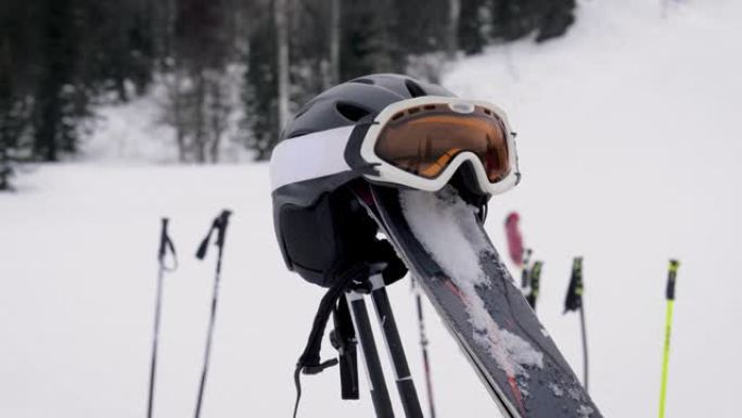 滑雪板从雪中伸出，在滑雪者的斜坡背景上有头盔和面罩