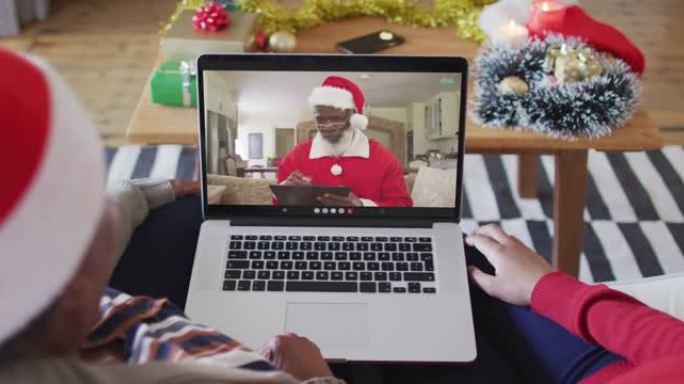 非裔美国母亲和女儿使用笔记本电脑与屏幕上的圣诞老人进行圣诞节视频通话