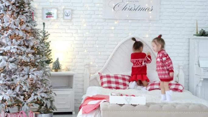 孩子们跳起来，在父母卧室的床上玩得开心，上面装饰着圣诞节，背景是砖白墙。