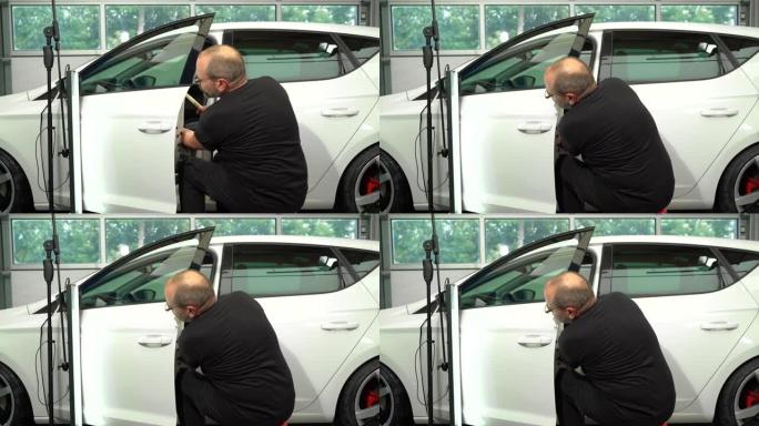 汽车修理厂汽车左车门表面凹痕修复视频过程。技术人员正在使用工具进行无油漆凹痕修复。