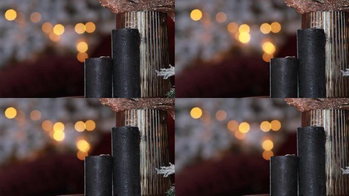 模糊灯光背景上的两支黑色圣诞蜡烛。圣诞场景由新年树和装饰品组成。