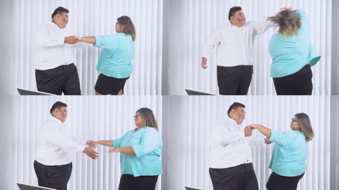 快乐的超重商务夫妇在办公室跳舞