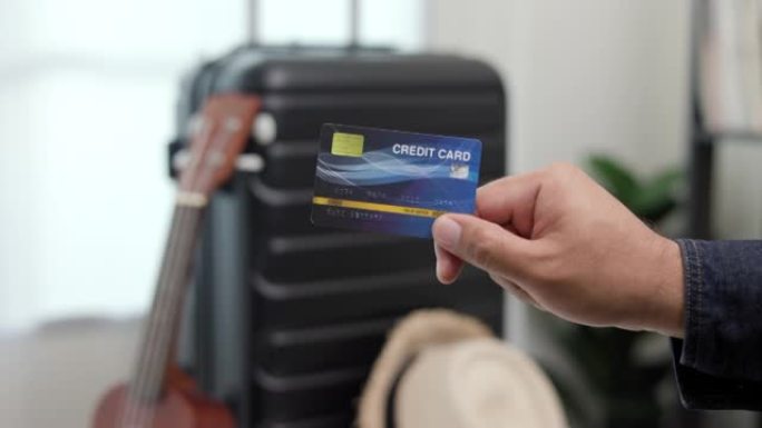 特写旅行者手汉展示信用卡支付的旅行。背景上的拉杆包。旅行奖励点。游客会员卡计划