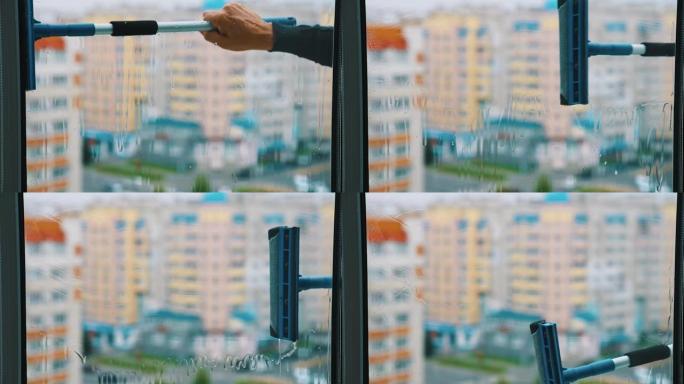 用清洁刷的手正在洗窗户。从城市中一座高层建筑的外面清洁塑料窗。从公寓看。
