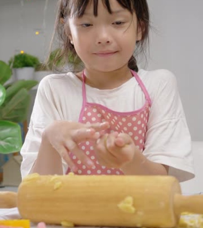 亚洲女孩拿着糕点面团，然后模制自制饼干庆祝圣诞节，生活方式概念。