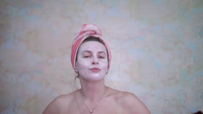 一名头上戴着毛巾的妇女涂了一个化妆品面膜，以恢复活力并抚平皱纹。水疗护理。对抗皱纹和皮肤老化。