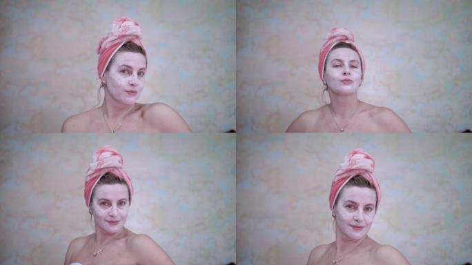 一名头上戴着毛巾的妇女涂了一个化妆品面膜，以恢复活力并抚平皱纹。水疗护理。对抗皱纹和皮肤老化。