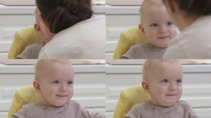 快乐的母亲带着微笑的婴儿在家，慈爱的妈妈亲吻她的儿子，8个月大的高加索孩子的脸特写