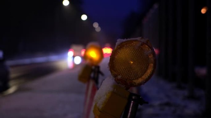 冬季晚上交通拥挤的繁忙结冰道路上，维修道路屏障橙色警示灯依次闪烁